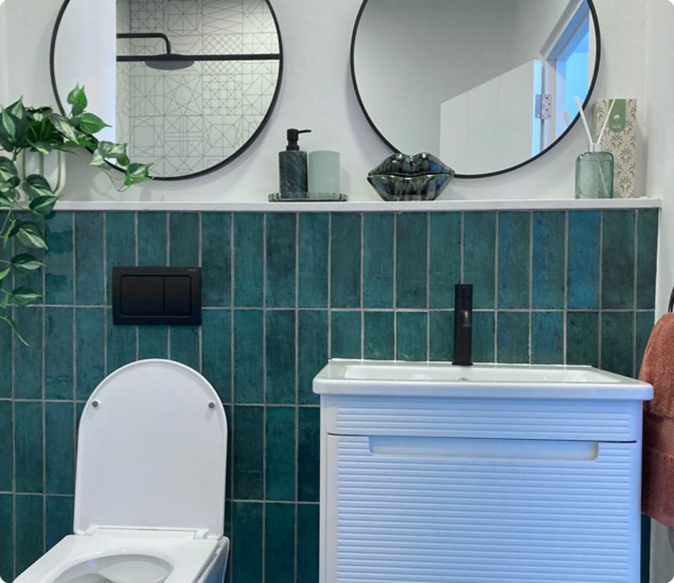 Verreweide bathroom, two round mirrors above teal tiled wall and basin.