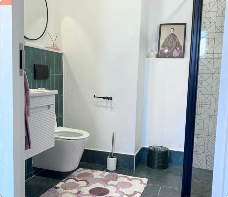 Verreweide bathroom, shower doorway and purple patterned bath mat.