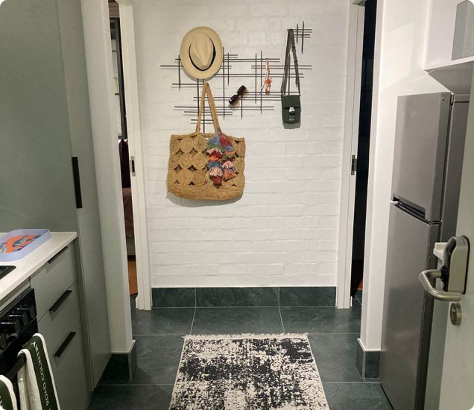 Main Road 2-bedroom kitchenette, white brick hallway, hat and hanging bag.