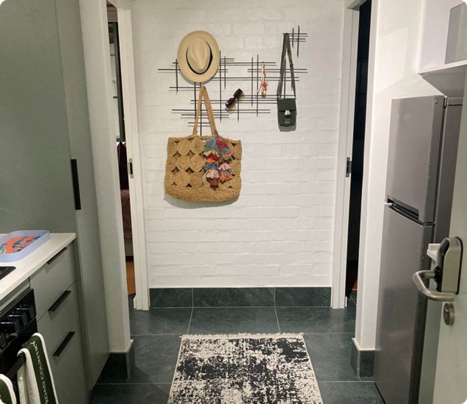 Main Road 3-bedroom kitchenette, frontal hallway crop with hat and hanging bag.