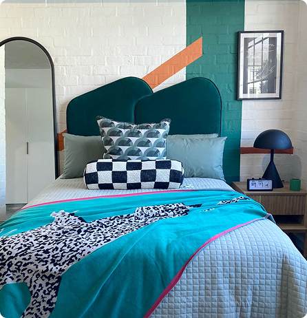 Bedroom with a teal bed and wall mural